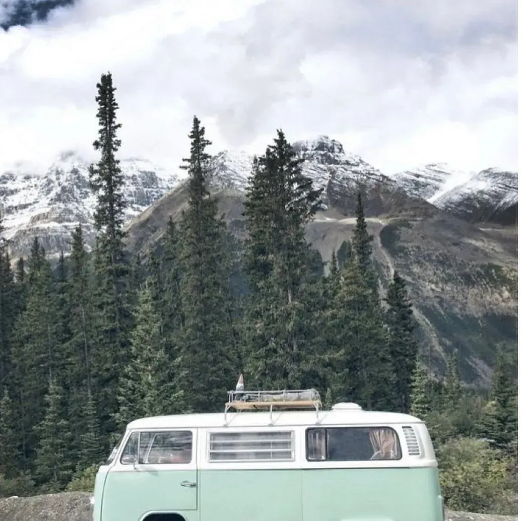 Una furgoneta verde está aparcada delante de una montaña nevada