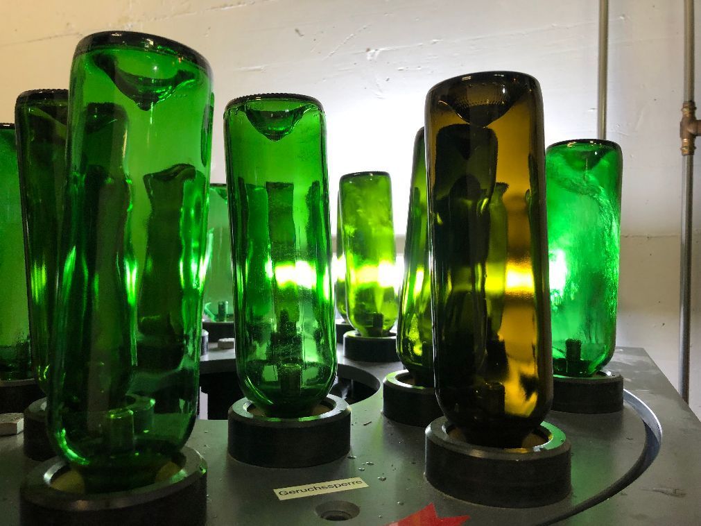 Wein und Trauben auf einem Tisch im Freien; zwei Weingläser, zwei Flaschen und zwei Trauben.