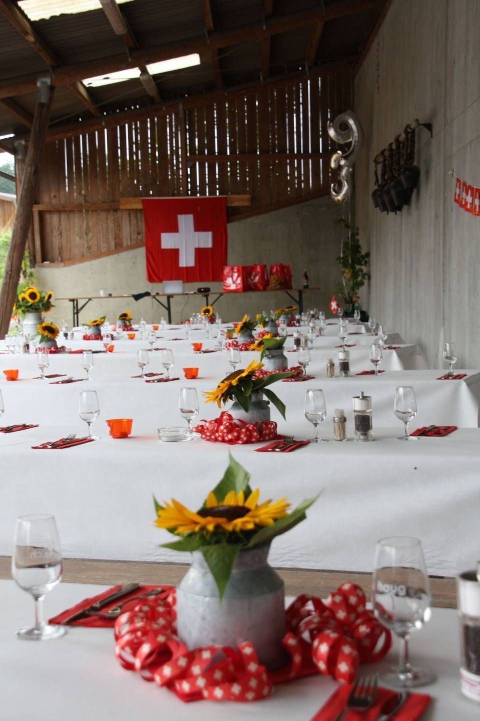 Für eine Feier gedeckte Tische, Schweizer Flagge und Sonnenblumen.