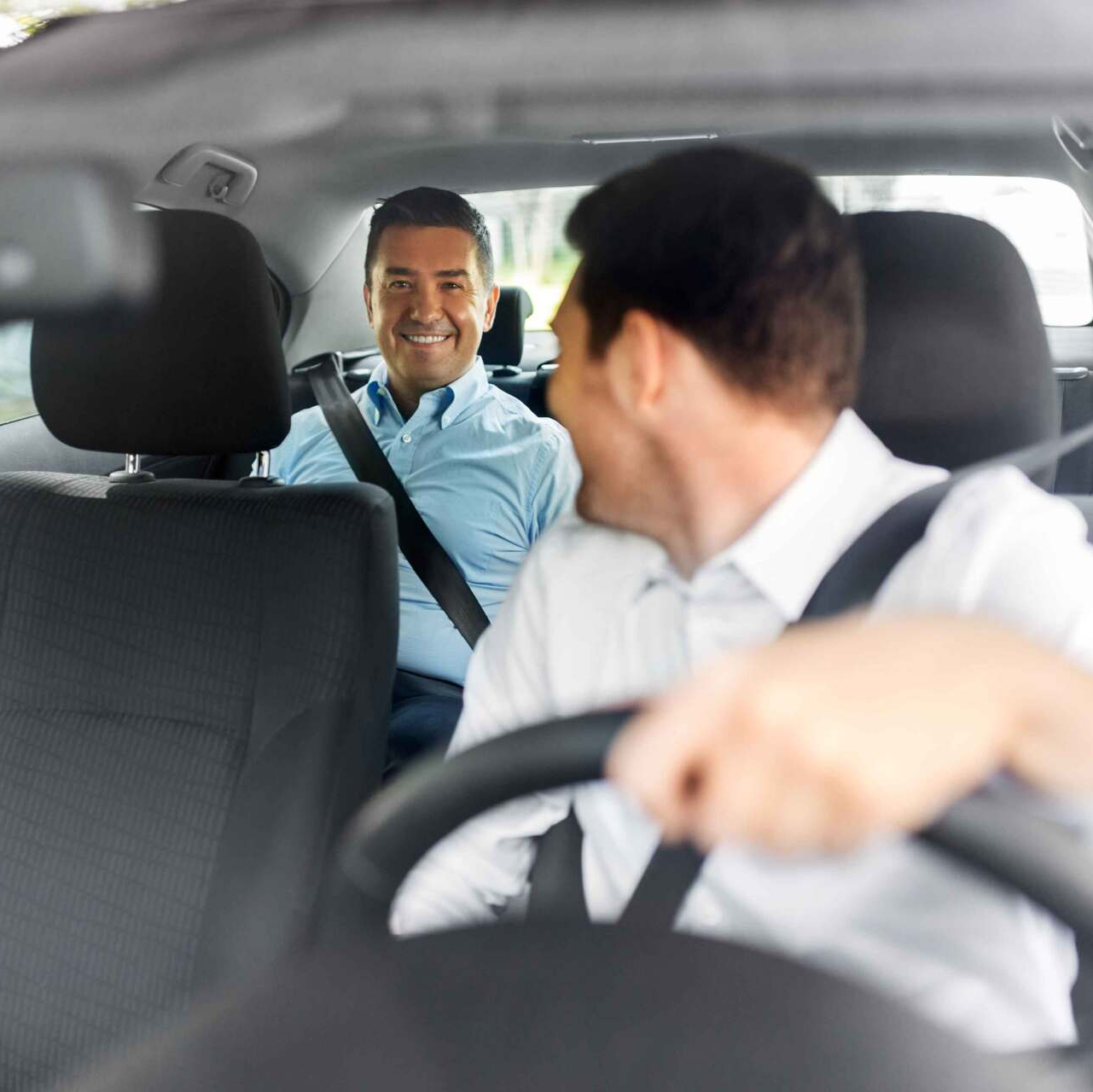 Un chauffeur retourné vers le passager qui le regarde en souriant
