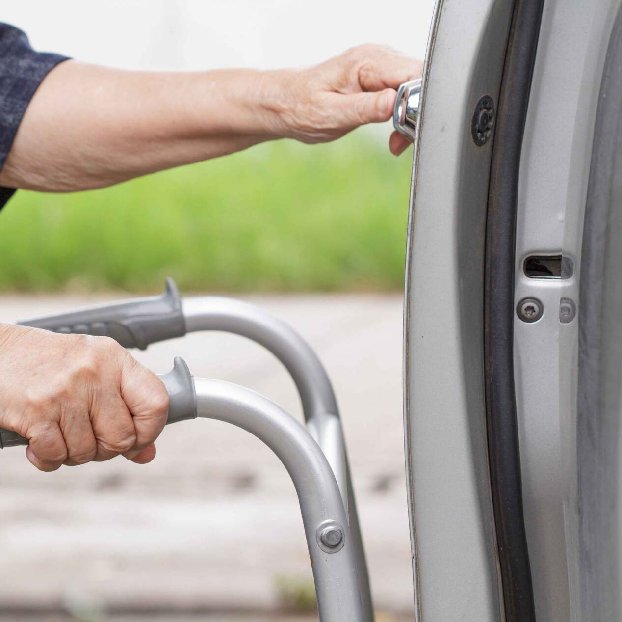 Personne âgée tenant un déambulateur et ouvrant une porte latérale de voiture
