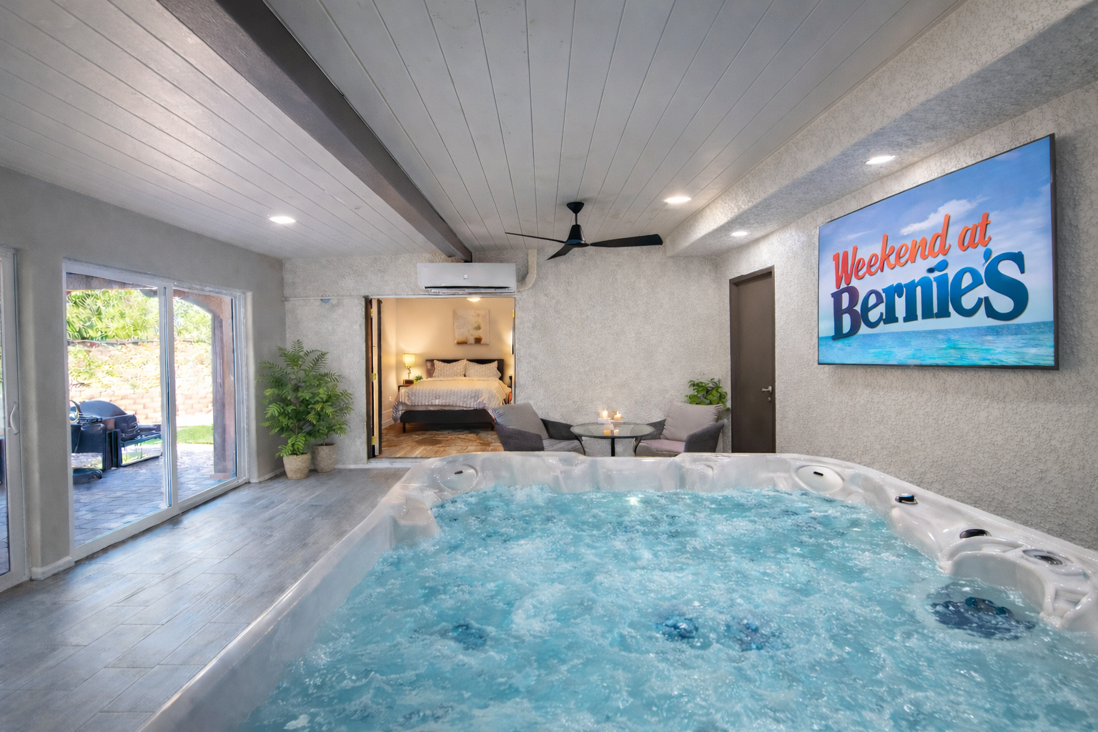 Indoor hot tub with a view of a bedroom, a movie screen displaying "Weekend at Bernie's," and a sliding glass door.