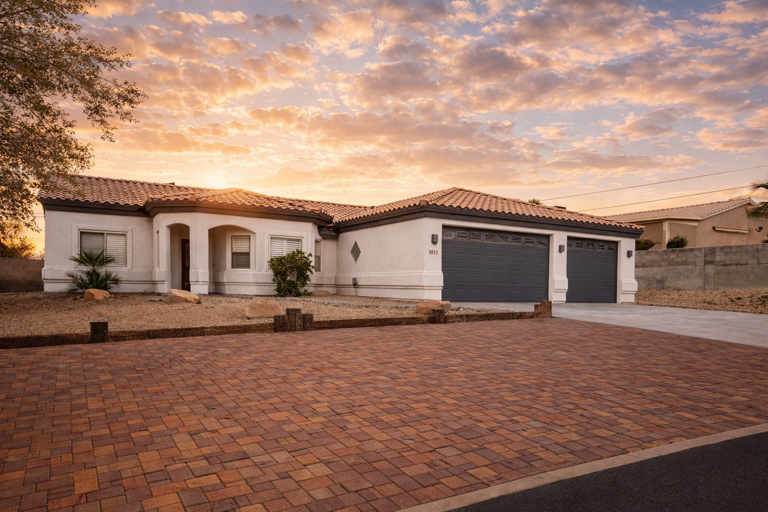 House with brick driveway for boats and RV's and two-car garage, under a sunset sky.