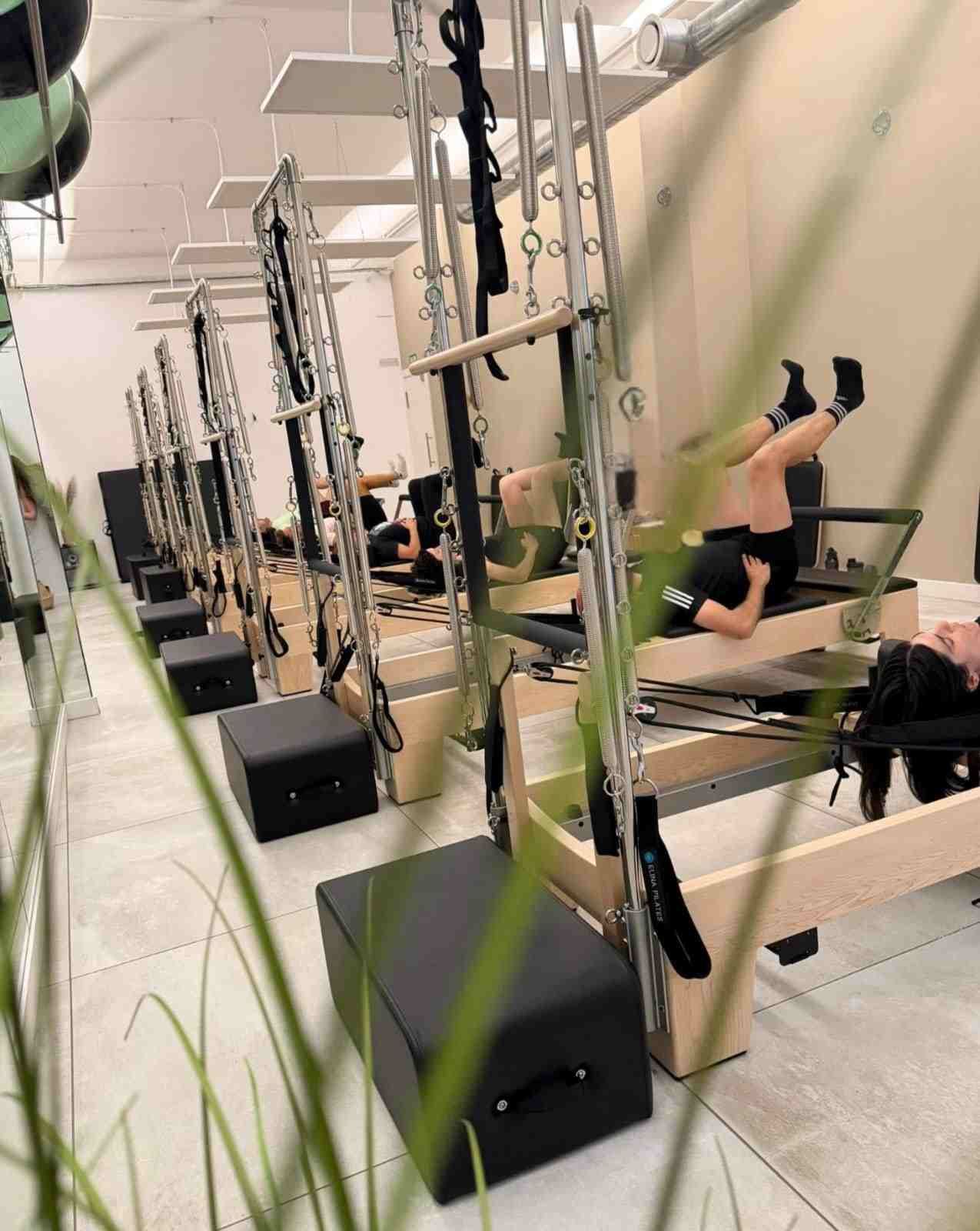 Estudio moderno de Pilates con máquinas reformer, espejos y una cálida iluminación cenital