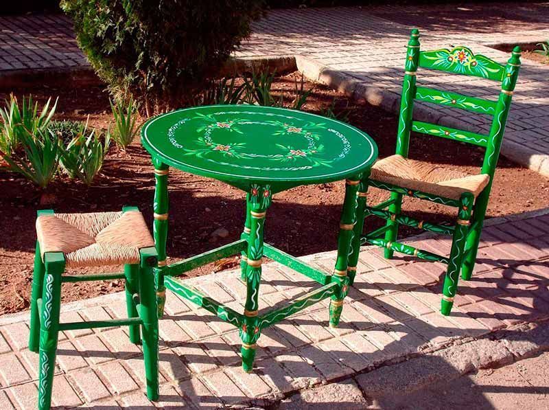 Dos sillas verdes y una mesa verde en una acera de ladrillos