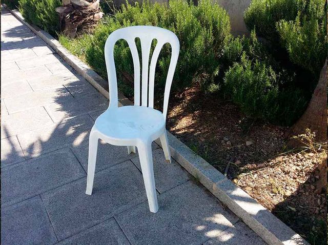 Una silla de plástico blanca está sentada en una acera.