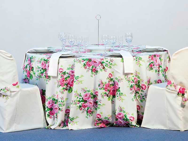 Una mesa con un mantel floral y sillas.