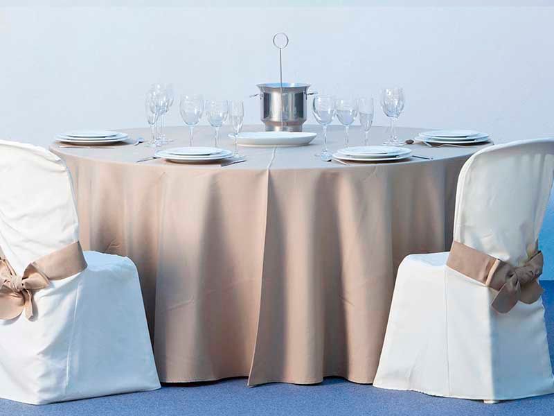 Una mesa con platos, vasos y un cubo de champán encima.