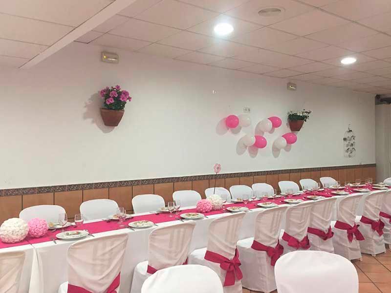 Una mesa larga y sillas en una habitación con globos en la pared.