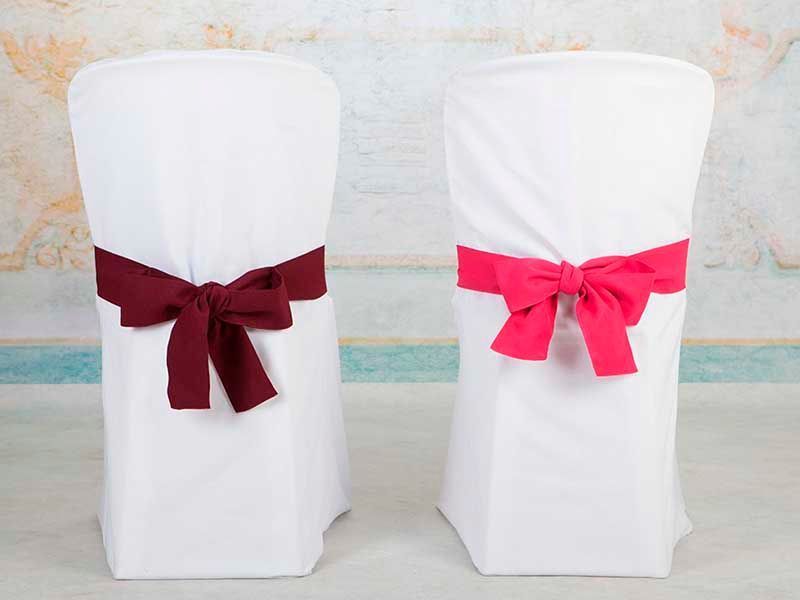 Dos sillas blancas con lazos rojos.