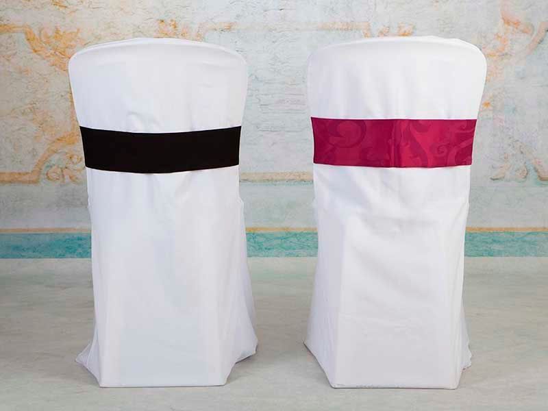 Dos sillas blancas con fajas negras y moradas están sentadas una al lado de la otra.