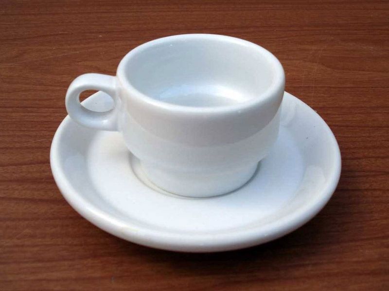 Una taza y un platillo blancos sobre una mesa de madera