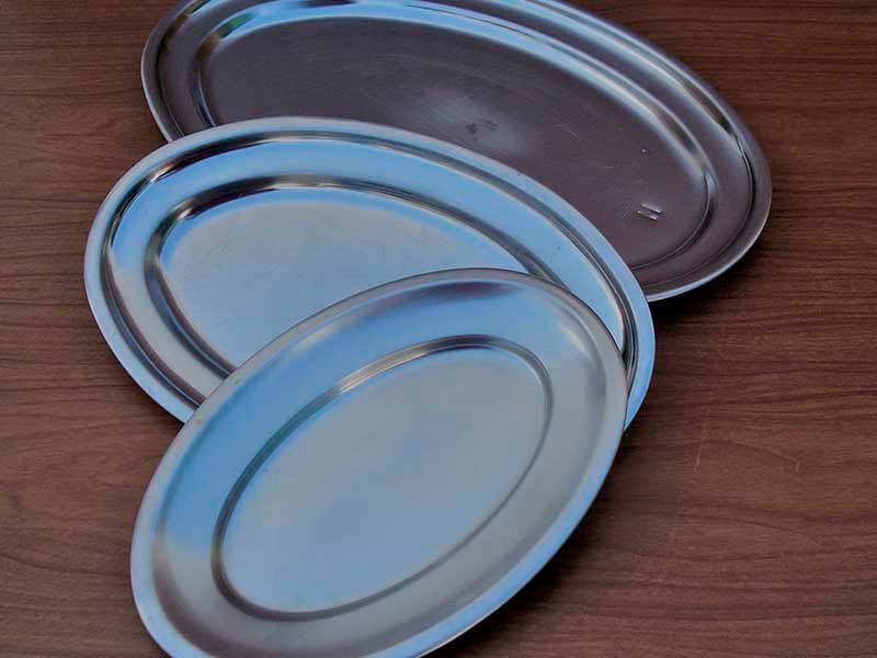 Tres placas de acero inoxidable se apilan una encima de otra sobre una mesa de madera.