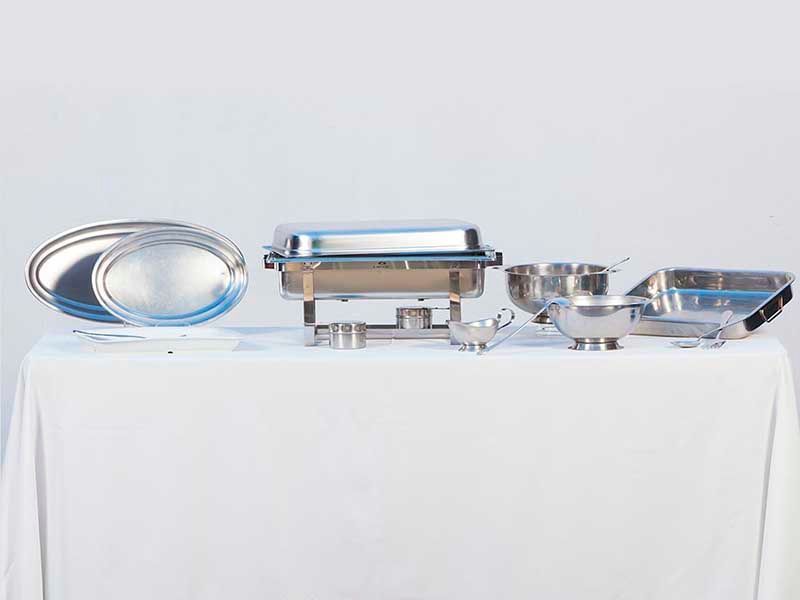 Una mesa cubierta con una variedad de platos de acero inoxidable para calentar alimentos.