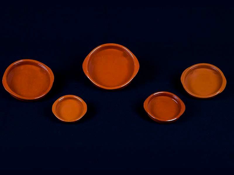 Un grupo de pequeños cuencos naranjas sobre un fondo azul oscuro.