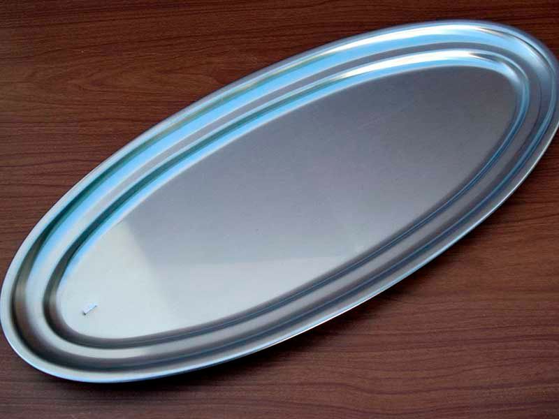 Una bandeja de acero inoxidable está sobre una mesa de madera.