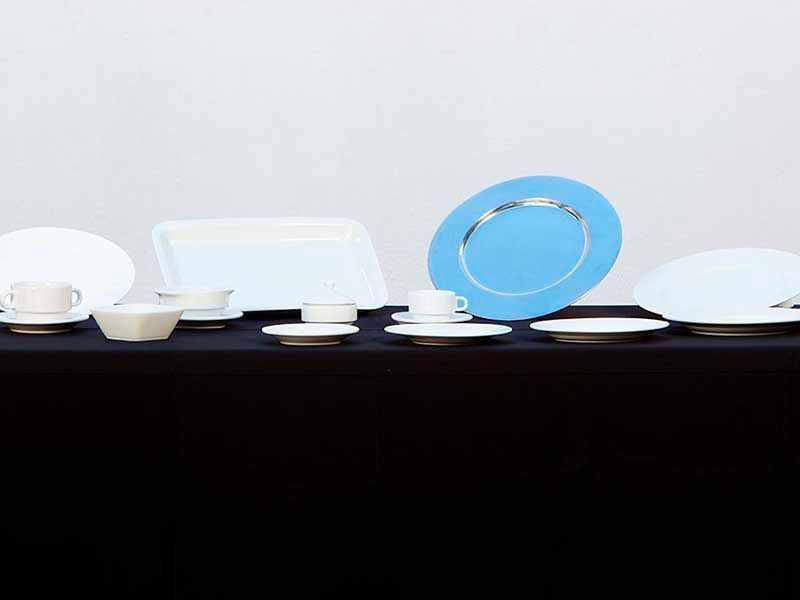 Una mesa cubierta con platos, tazas, platillos y un plato azul.