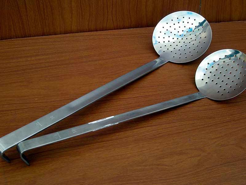 Dos cucharones de acero inoxidable están sobre una mesa de madera.