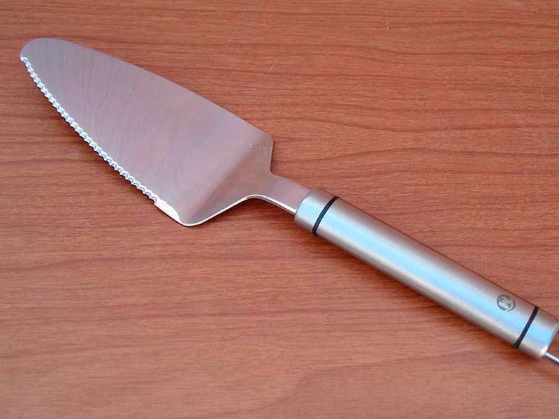 Una espátula de acero inoxidable para pasteles está sobre una mesa de madera.