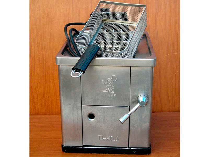 Una freidora de acero inoxidable está sobre una mesa de madera.