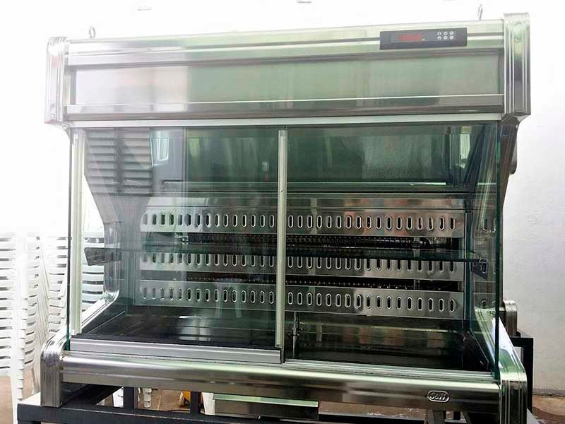 Un refrigerador de acero inoxidable con puerta de vidrio está ubicado encima de una mesa.