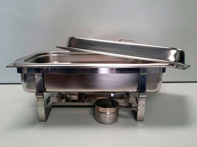 Un plato de acero inoxidable para calentar alimentos se encuentra encima de una mesa.