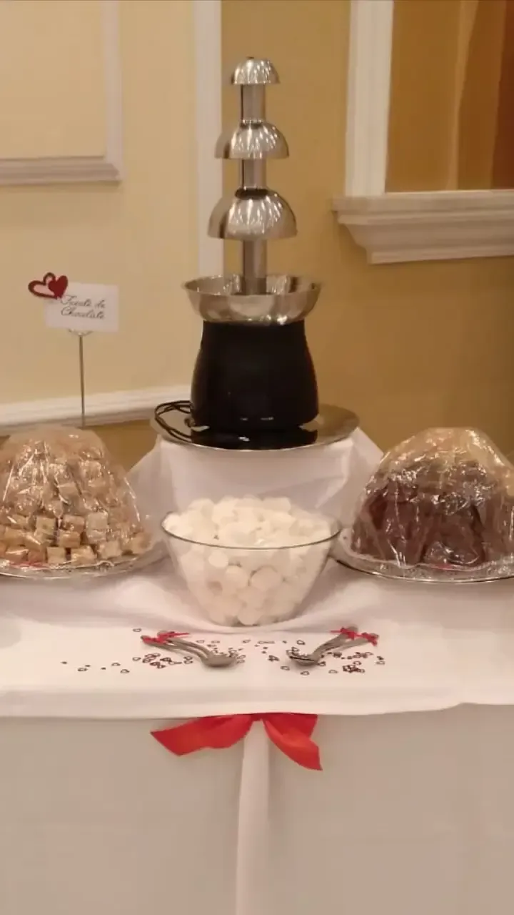 Una mesa con una fuente de chocolate y un bol de glaseado.