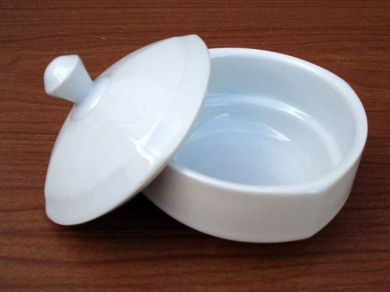 Un pequeño recipiente blanco con tapa sobre una mesa de madera.