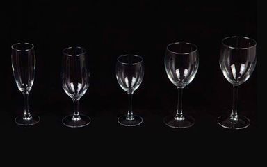 Una fila de copas de vino de diferentes tamaños sobre un fondo negro.