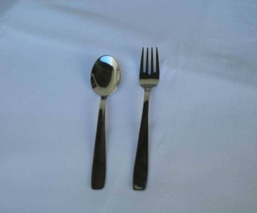 Una cuchara y un tenedor están sobre un paño blanco.