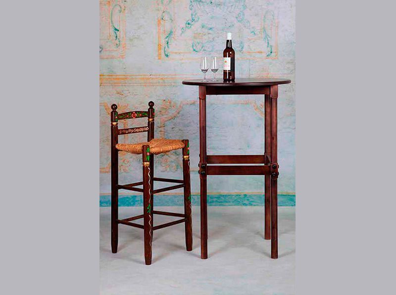 Un taburete de bar y una mesa con una botella de vino encima.