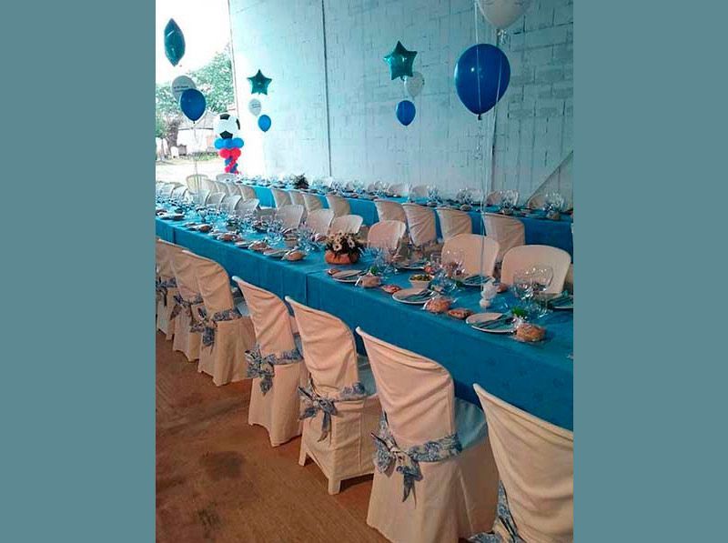 Una mesa larga con sillas azules y blancas y globos en la pared.
