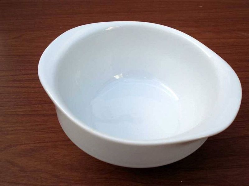 Un cuenco blanco está sobre una mesa de madera.