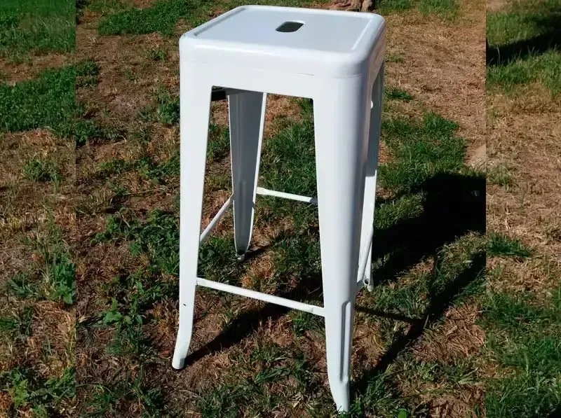 Un taburete blanco está sentado en el césped de un campo.
