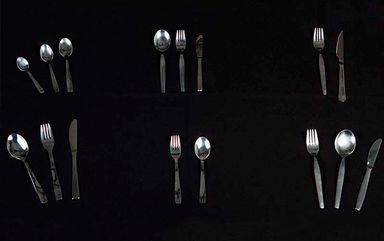 Una fila de cubiertos que incluye tenedores, cucharas y cuchillos sobre un fondo negro