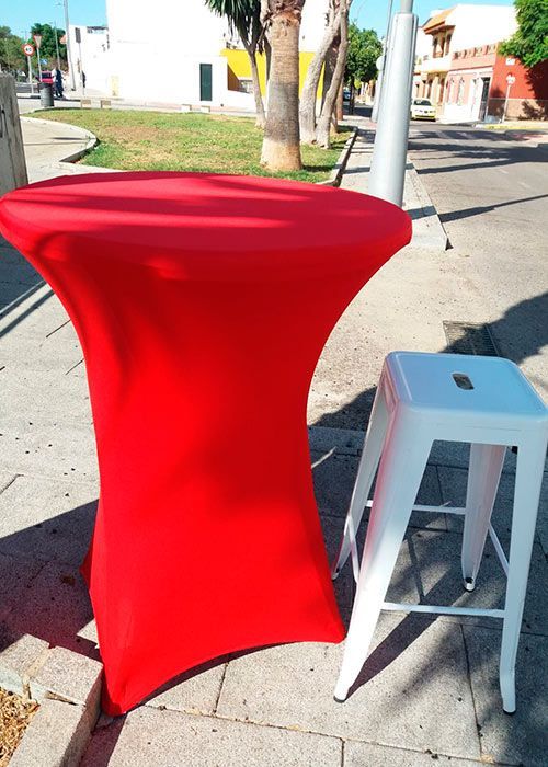 Un mantel rojo se encuentra junto a un taburete blanco.
