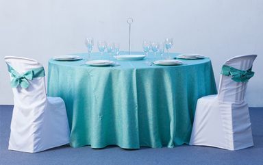 Una mesa con un mantel azul y sillas blancas.