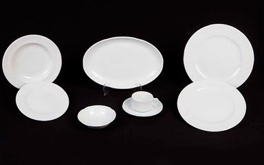 Un grupo de platos y cuencos blancos sobre un fondo negro.