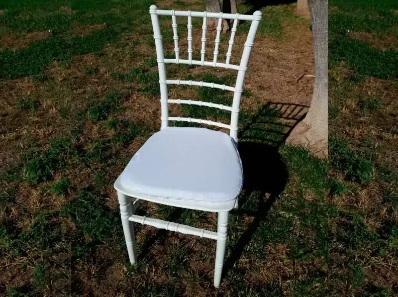 Una silla blanca está sentada en el césped al lado de un árbol.