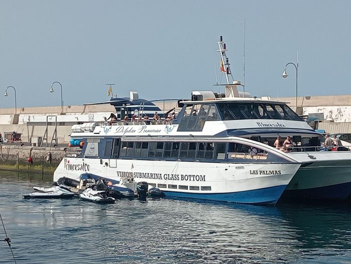Dos transbordadores blancos de pasajeros atracados en un puerto, con pequeñas motos acuáticas en primer plano.