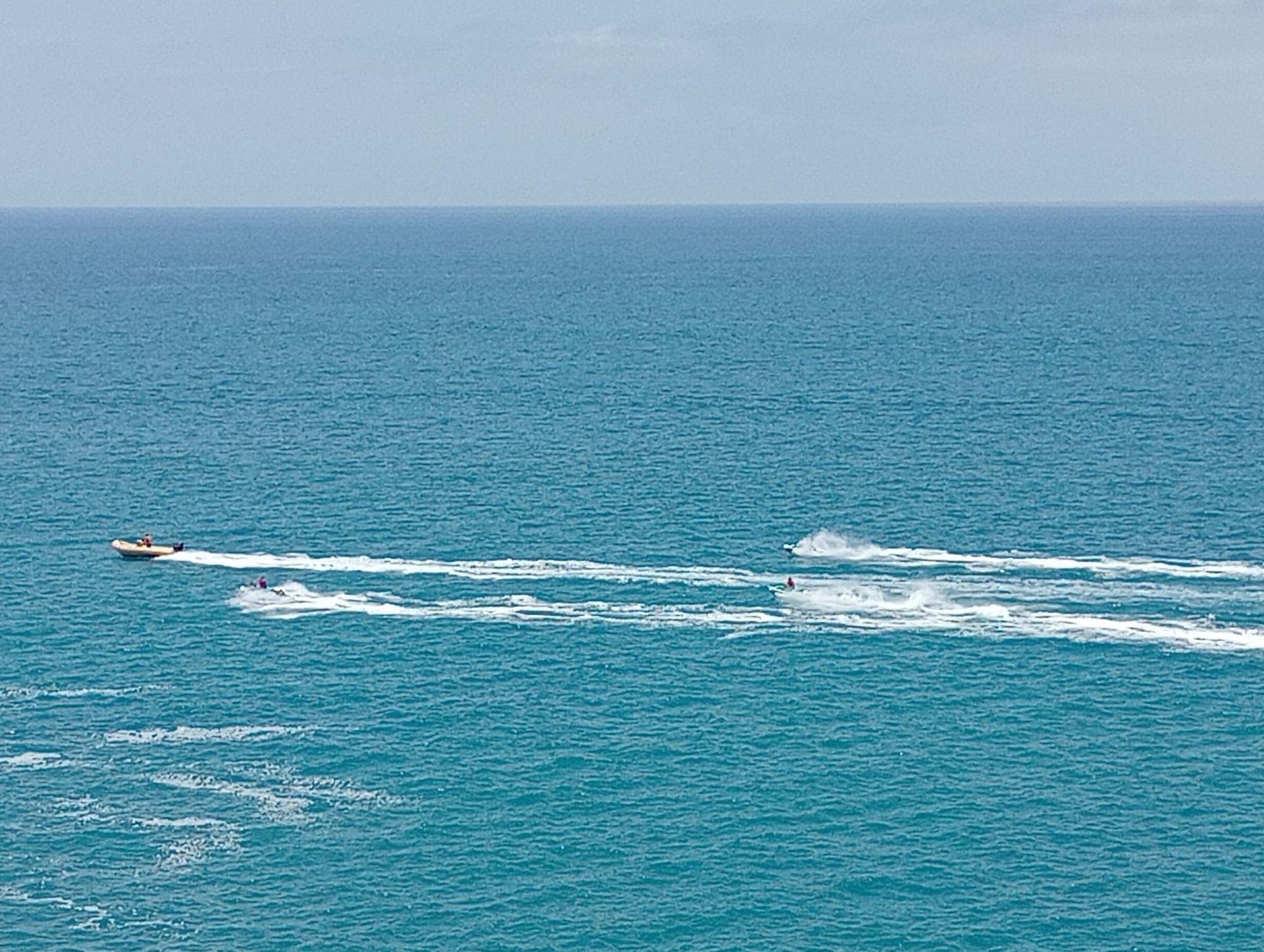 Una lancha motora surca el océano turquesa, dejando una estela blanca.