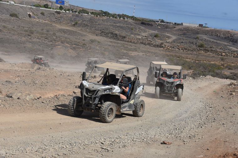Dos buggies todoterreno circulando por un sendero rocoso y polvoriento en un paisaje árido.