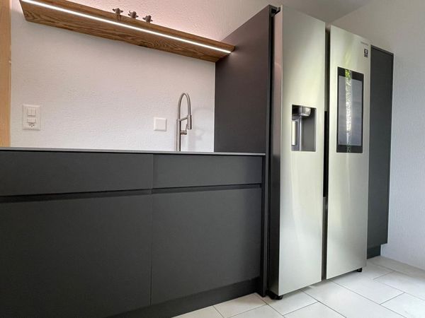 Moderne Küche mit grauen Schränken, Edelstahlkühlschrank und Armatur.