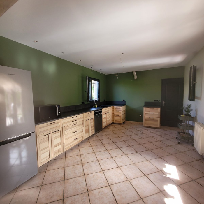 Une cuisine avec armoires en bois et un réfrigérateur en inox