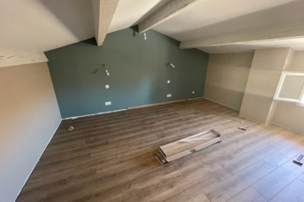 Une pièce vide avec un parquet et une fenêtre.