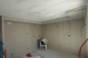 Une pièce vide avec une fenêtre et des cloisons sèches sur les murs