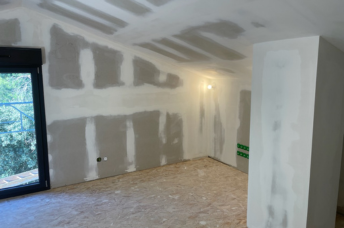 Une pièce vide avec une fenêtre et des cloisons sèches sur les murs