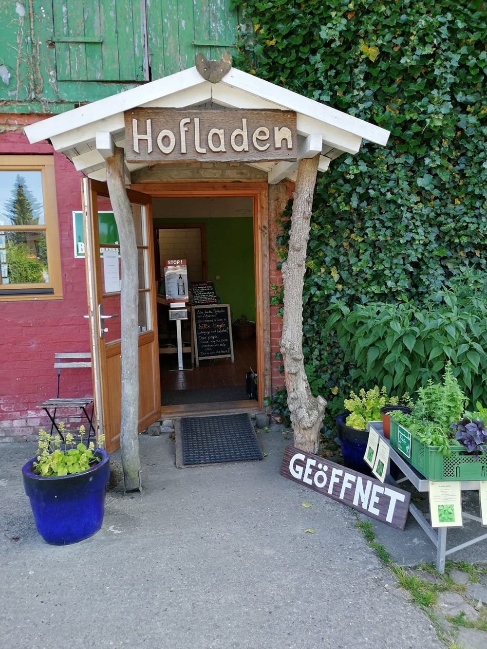 Der Eingang zu einem Bauernhof mit einem Schild mit der Aufschrift „Hofladen“.