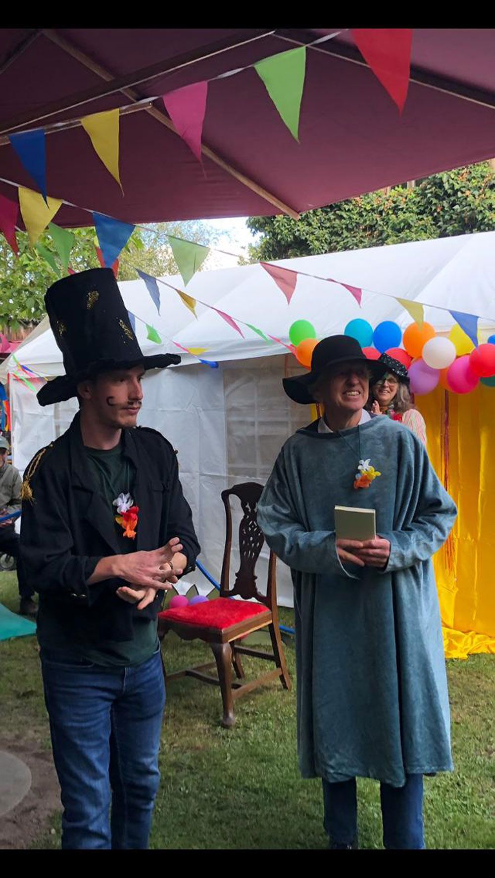 Zwei Männer stehen nebeneinander vor einem Zelt mit Luftballons.
