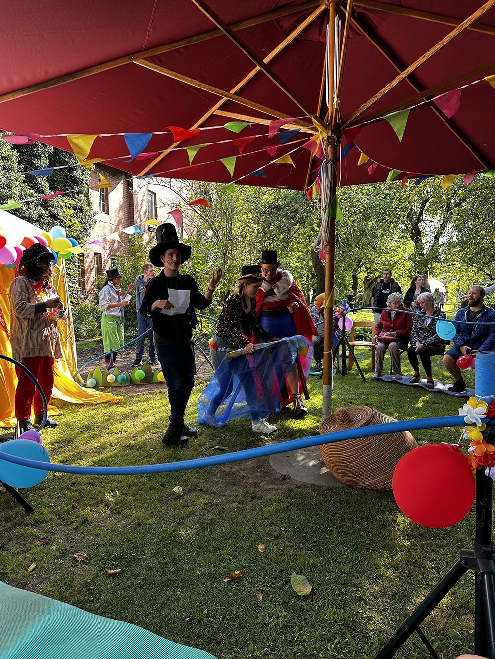Eine Gruppe von Menschen steht in einem Park unter einem Regenschirm.